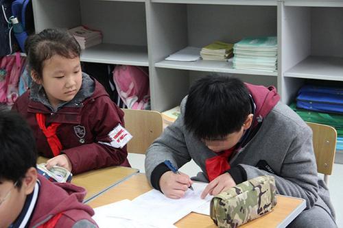 2017年11月29日，上海市闵行区平阳小学，自闭症男孩亨亨（右一）在写作业。本文图片均为 澎湃新闻记者 李菁 摄