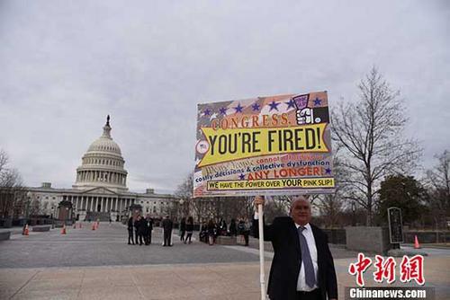 资料图：当地时间1月22日，美国人戴维·迪普斯基（David Dypsky）在美国国会前举牌抗议政府停摆。 中新社记者 邓敏 摄