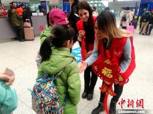 图为外国留学生志愿者向旅客赠送“福”字和中国结。 刘鹏 摄