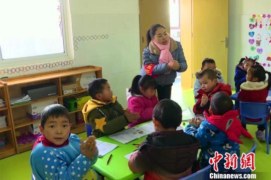 许春华在教室里与小朋友一起互动。