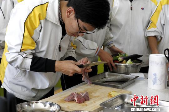 图为青海师范大学附属中学厨艺课，一位同学正在跟牛肉“较劲”。　张海雯 摄