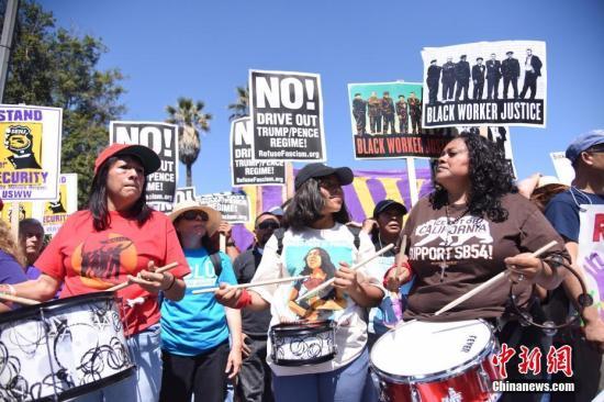 资料图：当地时间20117年5月1日，美国洛杉矶举行游行，移民手举标语、高呼口号，表达自己的诉求。 中新社记者 张朔 摄