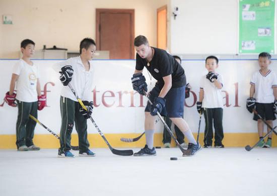 2017年9月7日，武汉冰龙国际冰球俱乐部俄罗斯籍教练阿纳托利（左三）为小学员指导技术动作。