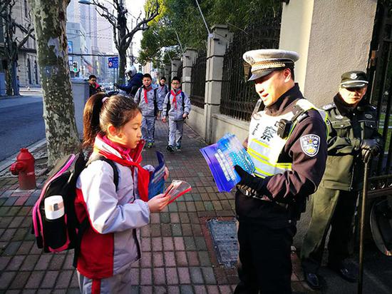 民警向小学生发放交通安全宣传单。