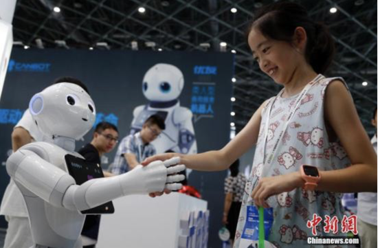 资料图：一位女孩在和机器人握手交谈。汤彦俊 摄