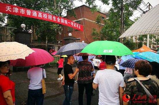 天津市第五十四中学考点外，不少家长撑伞站在门口等候、张望。崔新耀/摄
