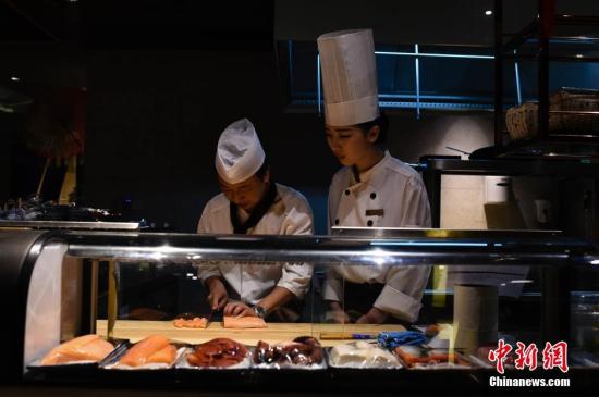 资料图:一名女生在学习日本料理。