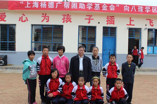 在慈善企业家的帮助下，杨德广筹资200万元，专门用于资助甘肃、四川地区贫困小学生营养午餐。这是杨德广与甘肃环县一学校学生合影（摄于2014年9月12日）。