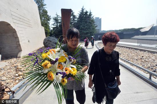 南京大屠杀遇难者彭玉珍家属献上鲜花。 图片来源：视觉中国