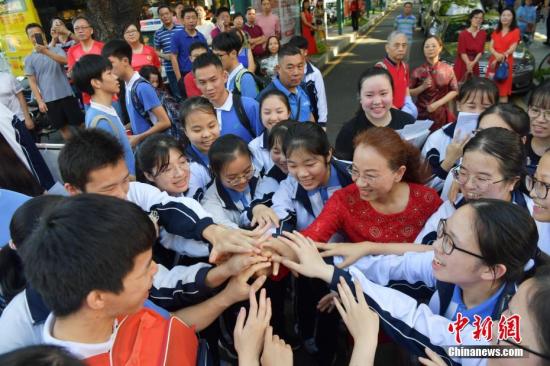 6月7日，在2019年全国高考深圳市福田中学考点，老师与考生一起加油。中新社记者 陈文 摄