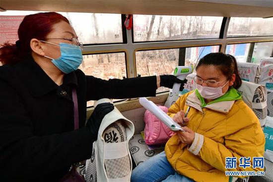 山西省静乐县第一中学校车上的工作人员在给李彦昀（右）测量体温（3月25日摄）。 新华社记者 曹阳 摄