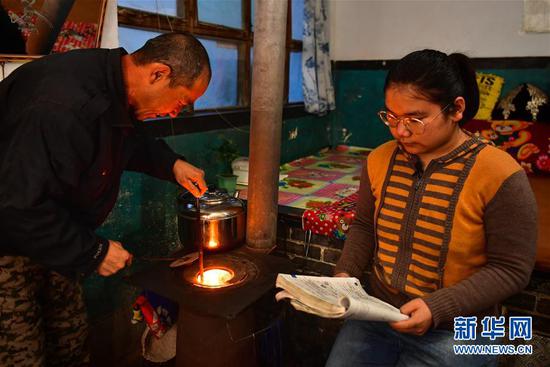 李彦昀（右）在静乐县新开岭村的家里一边烤火一边复习（3月23日摄）。 新华社记者 曹阳 摄