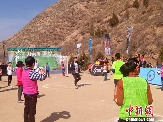 2018年3月，甘肃陇西县永吉乡河口小学生们和“活力校园”选派的外籍教练一起玩“趣味足球”游戏。（资料图）　钟欣　摄