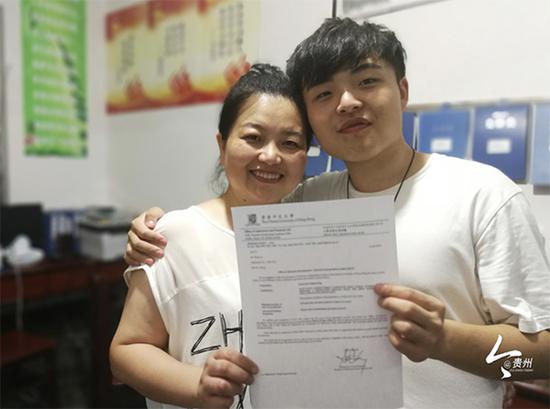 张杰举着香港中文大学的录取通知书和母亲合影留念。 图片来源：今贵州新闻客户端