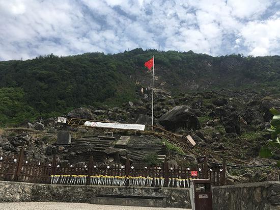 北川县老县城茅坝校区遗址上，只剩下一根旗杆和一个篮球架，成兴凤在儿子遇难的地方十年里连续更新挂横幅。澎湃新闻记者 王万春 摄