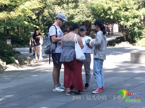 图为小组成员在灵隐寺景区口与游客们交谈。中国青年网通讯员 王丽慧 摄