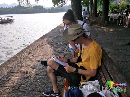 图为小组成员为受访游客详细解释每个选项。中国青年网通讯员 王丽慧 摄