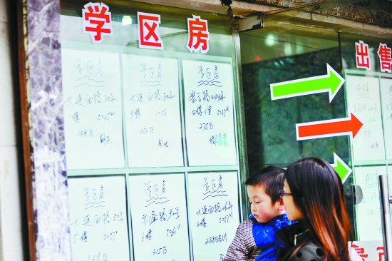 2015年3月18日，上海，一位家长带着孩子在中介门口看“学区房”房源CFP供图（资料图片）