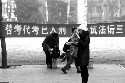 2015年12月26日，中国人民大学研究生考点，考生在“替考代考已入刑，以身试法请三思”标语下看书准备考试。图/东方IC
