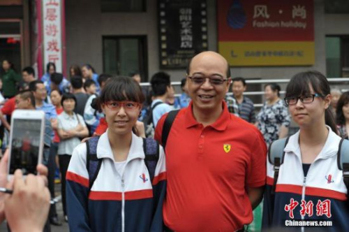 北京市陈经纶中学考点外，一名老师与即将参加考试的一对双胞胎女孩合影。 中新网记者 李泊静 摄