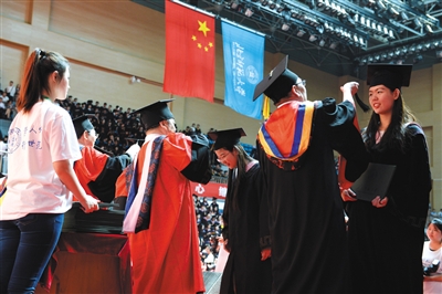 25日，毕业典礼上，北师大的老师为获得学士学位的本科毕业生拨穗。新京报记者 吴江 摄