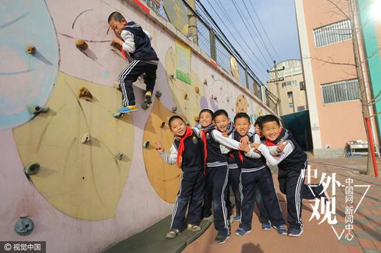 2013年12月4日,北京,为培养男孩的阳刚之气,朝阳实验小学启动“小男子汉”培养计划,为男孩专门开设课程,给男孩“加钢”。图为朝阳实验小学的学生在老师的指导下,进行攀岩比赛。(视觉中国)