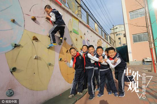 2013年12月4日，北京，为培养男孩的阳刚之气，朝阳实验小学启动“小男子汉”培养计划，为男孩专门开设课程，给男孩“加钢”。图为朝阳实验小学的学生在老师的指导下，进行攀岩比赛。（视觉中国）