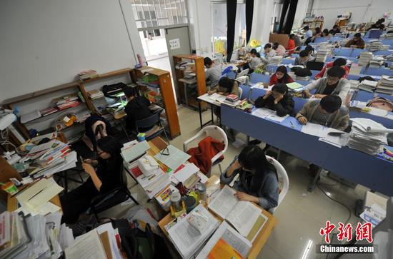 12月22日，福州一所大学校园内，考研专用教室里的桌面上堆满了学生们的各种复习资料。 张斌 摄