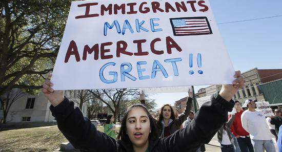 一名女子手持“移民让美国伟大”的标语参加游行