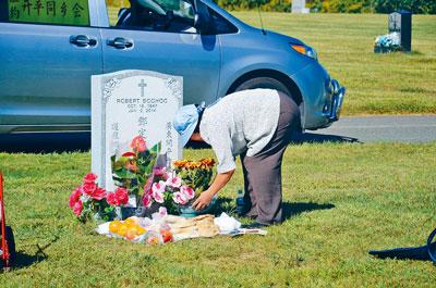 为亲人扫墓寄托的是思念及祝愿，图为一名华人在亲人墓前献花。（美国《星岛日报》）