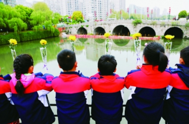 昨天,一群小学生手持鲜花,在九龙桥畔纪念“四一〇惨案”烈士牺牲九十周年