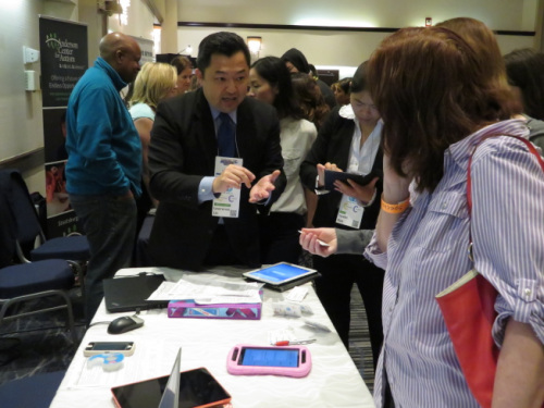 林欣(左)为参观者讲解公司设计的App。(美国《世界日报》/陈小宁 摄)
