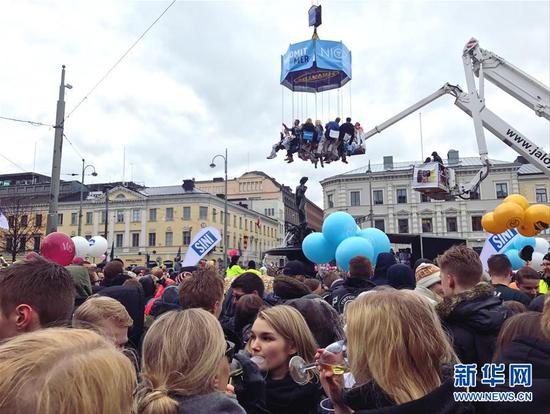 4月30日，在芬兰赫尔辛基，人们观看坐在吊车上的学生代表为阿曼达塑像戴帽子。