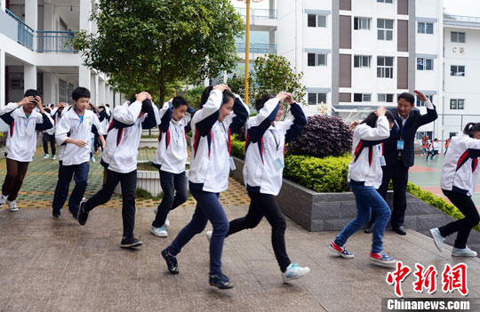 资料图：4月22日，广西龙胜各族自治县初级中学开展了突发事件安全应急疏散演练。图为学生们用双手护住头部快速向学校安全场所撤离。中新社发 石农兵 摄