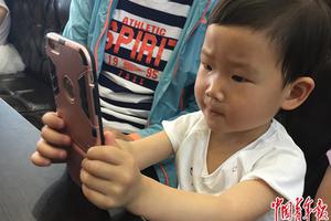 5月14日，天津一家餐厅，一名3岁儿童在等餐期间，用家长的手机聚精会神玩儿游戏。中国青年报·中青在线记者  张国/摄