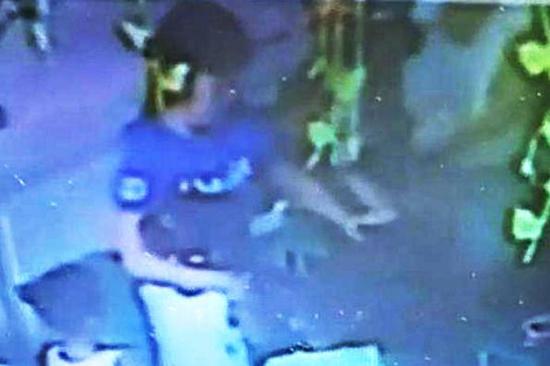 老师左手阻挡田某，右手紧紧搂住孩子，即便这样，田某还是打中两次。视频截图