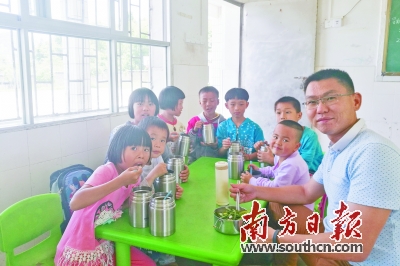 张旭辉（右）募捐而来的爱心饭盒使学生吃上热腾腾的饭菜。南方日报记者 孙俊杰 摄.jpg