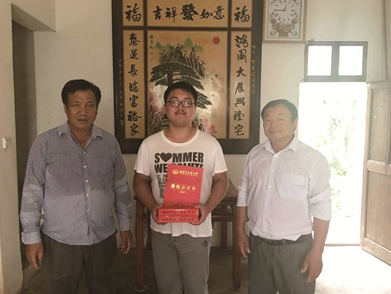 村委干部为考上大学的农家学子送去千元奖励金。