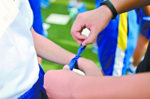 广州市真光教育集团六校区开学典礼在广州市真光中学白鹤洞校区举行。小学一年级、初一级、高一级新生2000多人通过不同的形式纪念人生新阶段的启程。图为师长在初一级新生手腕上系上蓝丝带。 骆昌威、曾伟康 林志彦摄