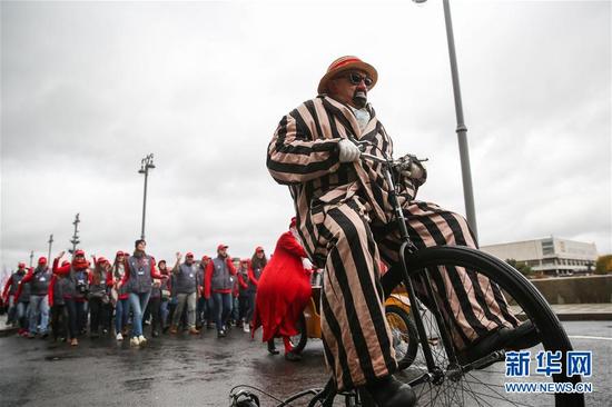 10月14日，一名打扮成小丑的青年骑车参与游行。