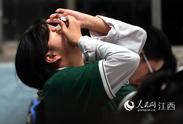 看书时间长了,一名学生正在滴眼药水。人民网 时雨/摄
