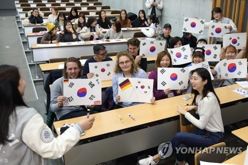  资料图片：2月27日，在首尔明知大学人文校区，外国人留学生手绘韩国国旗。(图片来源：韩联社，明知大学供图)