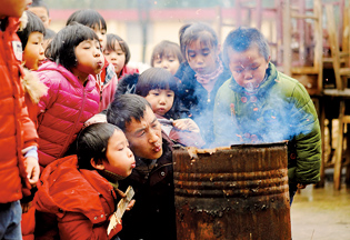 章站亮（前右）和黄泥小学的学生们一起生火（1月3日摄）。由于生火用的材料是废弃的桌椅或者枯叶，点火后要不停吹气才能烧得旺。