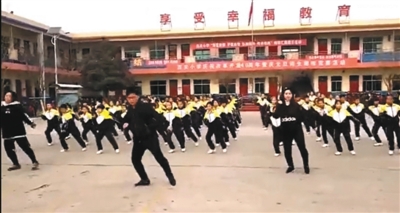 网络视频显示,校长张鹏飞在学校操场带领学生跳舞。视频截图