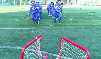 爱好打冰球的广中高一学生在操场上训练基本动作，为日后上冰场分组对抗做准备。