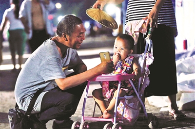 6月20日,老人拿着手机哄孩子