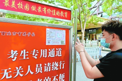 昨天，一位市民在北京育英学校高考点外观看“送考地图”。海淀交警为辖区内18个考点绘制了“送考地图”，涵盖了停车位、家长等候区等信息。本报记者 吴镝摄