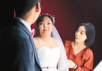 罗娴(右)正在指导农民工夫妇拍摄婚纱照。