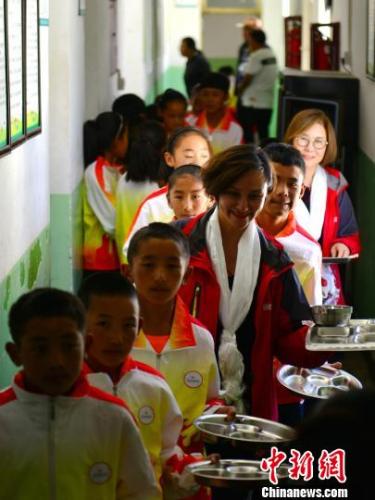 “跳水皇后”高敏(图中第四位)和西藏日喀则的孩子们一起排队、午餐。江飞波 摄