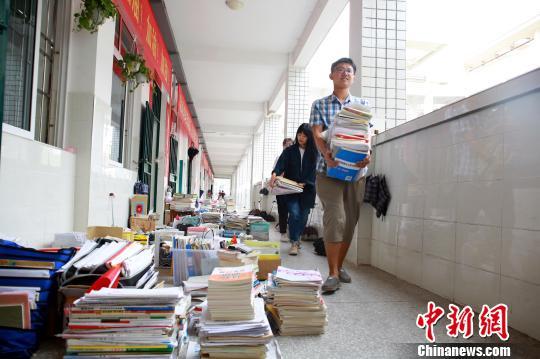 学生抱着书本从堆满书籍的走廊走过。　朱柳融　摄